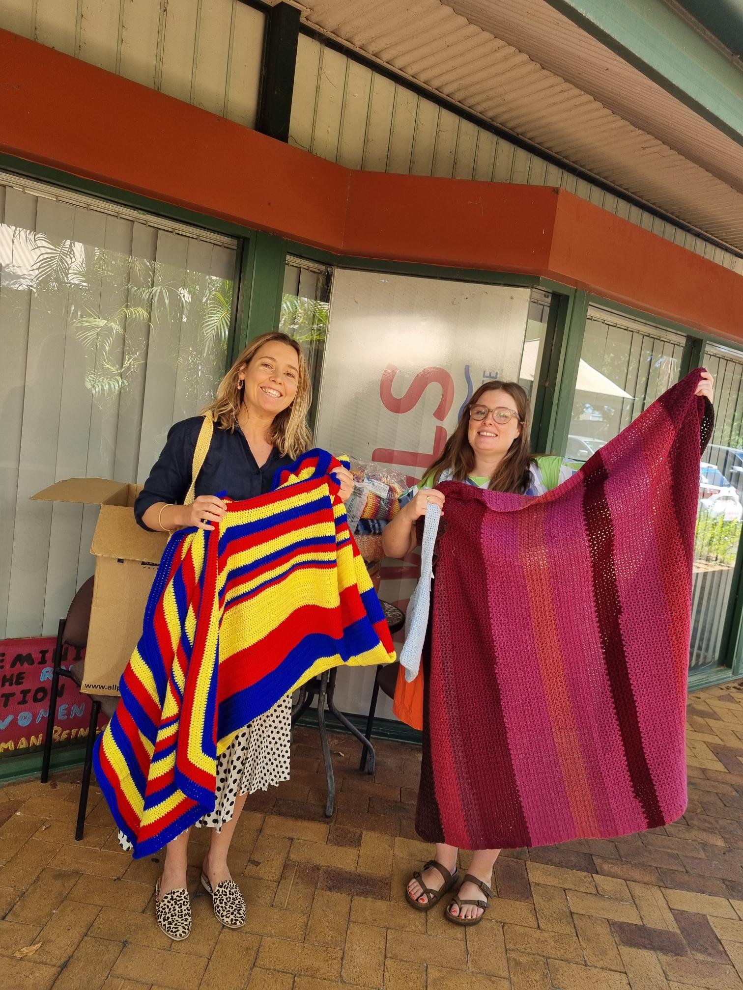 Knit4Charities volunteers with handmade blankets for donation